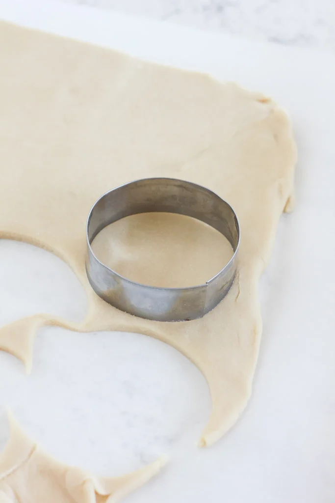 Pâte à biscuit avant cuisson avec un moule pour couper les biscuit en rond.