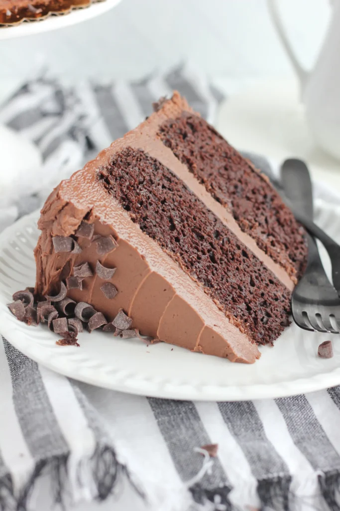 Pointe de gâteau au chocolat sur une assiette blanche avec ustensiles