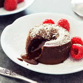 Un gâteau mi-cuit dans une assiette blanche juste à côté d'une cuillère