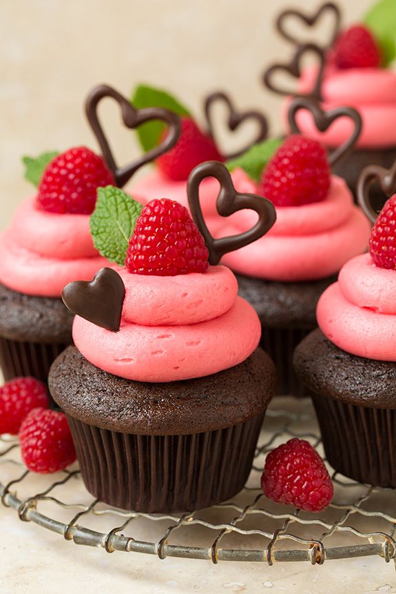 Cupcake aux chocolat avec du glaçage rose,une framboise et des petits coeur en chocolat noir
